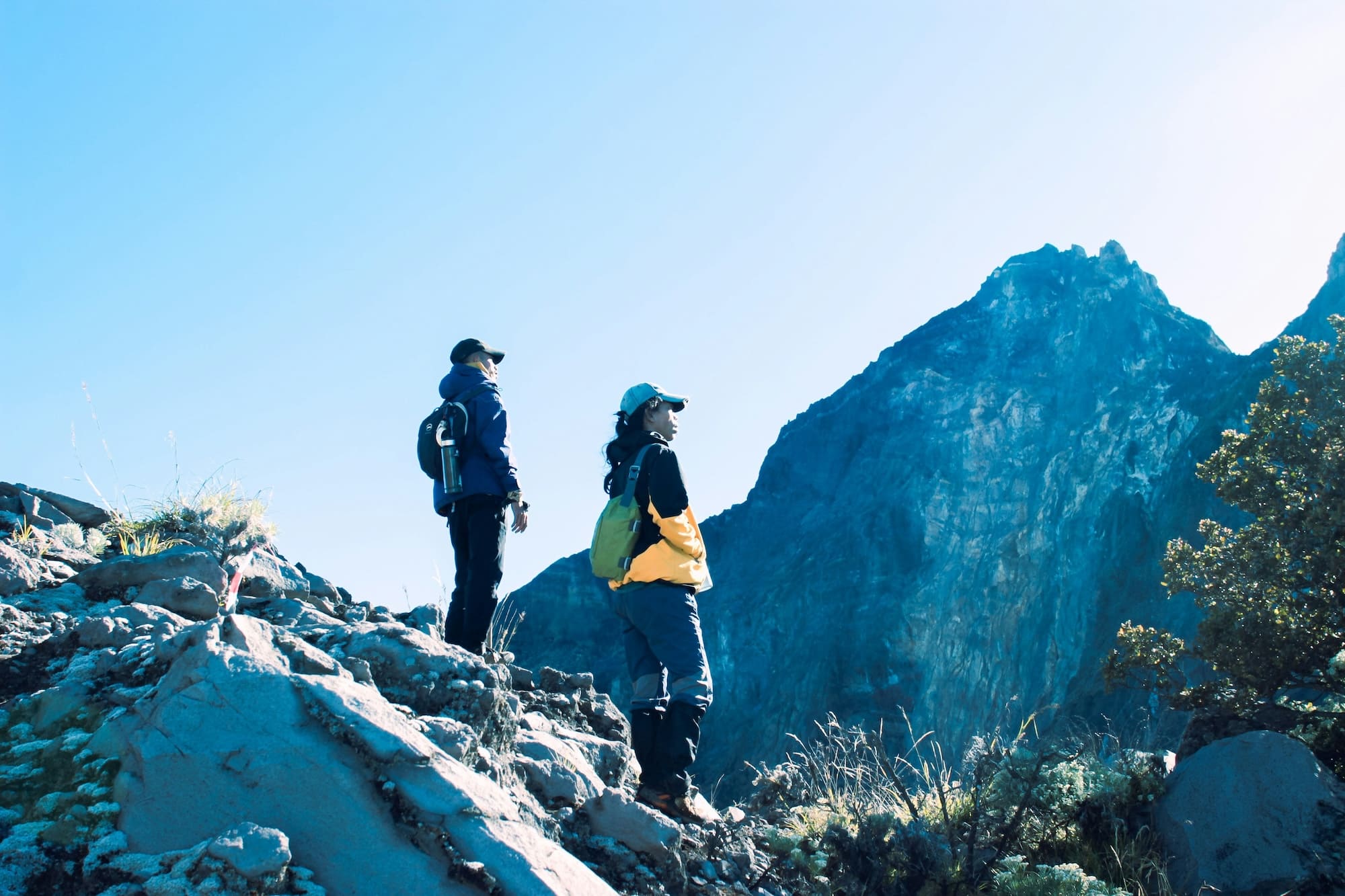 Zwei Wanderer mit Rucksäcken auf felsigem Vulkangelände am Mount Rinjani auf einer Lombok Reise