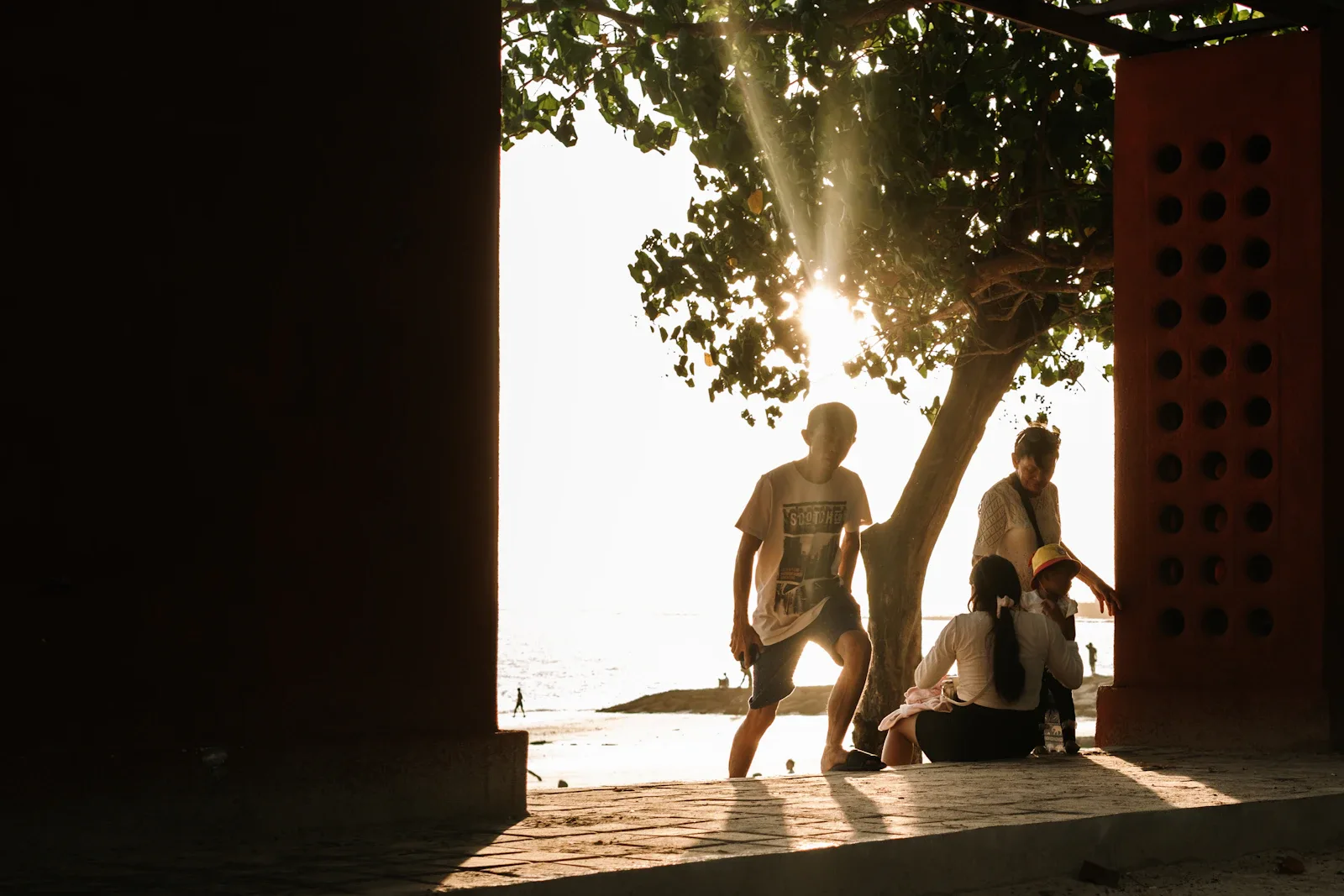 Familie beobachtet gemeinsam Sonnenuntergang am Strand von Bali, entspannte Atmosphäre einer gelungenen Bali mit Kindern Reise