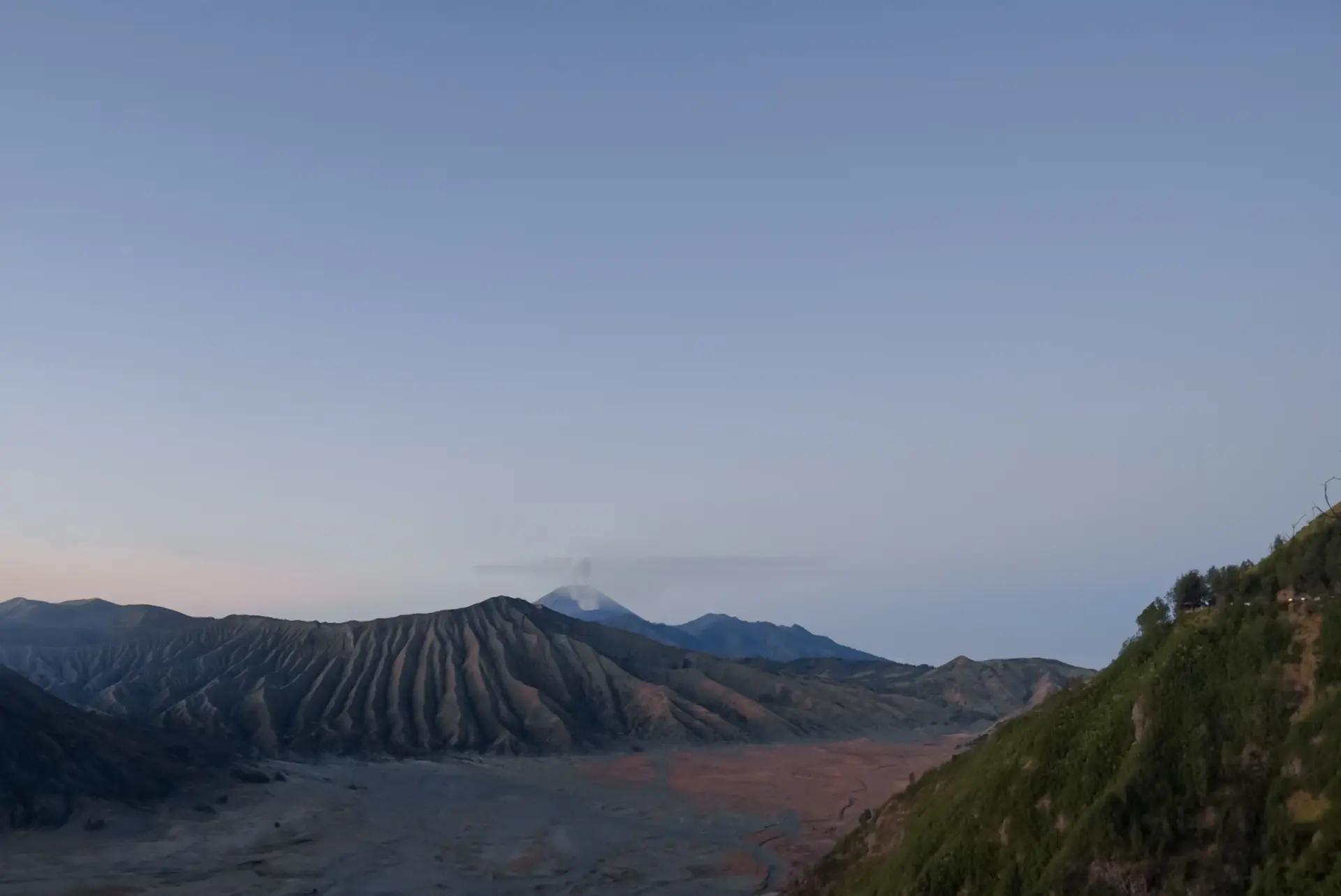 Panoramablick über die Bromo-Caldera bei Sonnenaufgang mit rauchenden Vulkanen und Aschewüste, Java, Indonesien