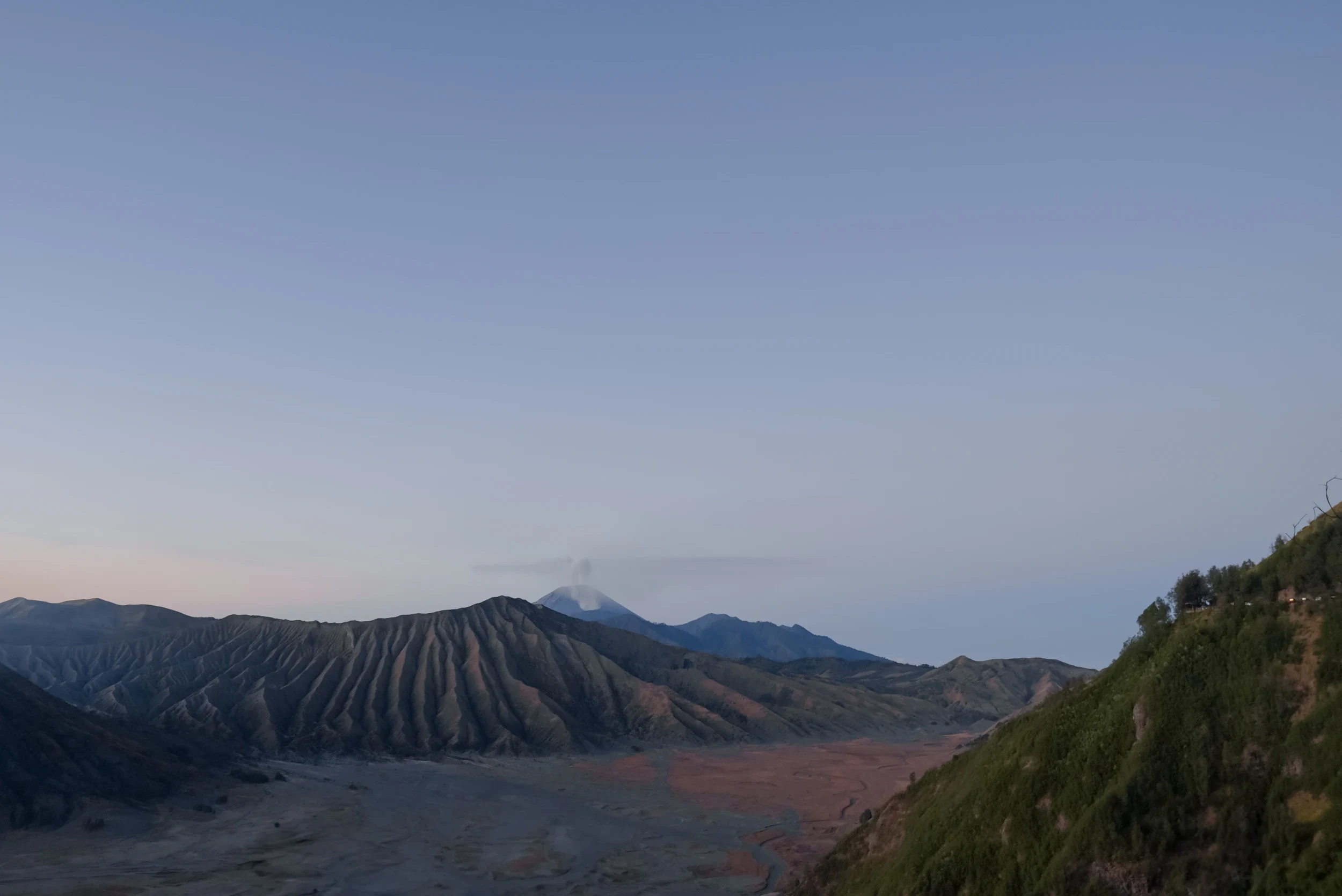 Panoramablick über die Bromo-Caldera bei Sonnenaufgang mit rauchenden Vulkanen und Aschewüste, Java, Indonesien